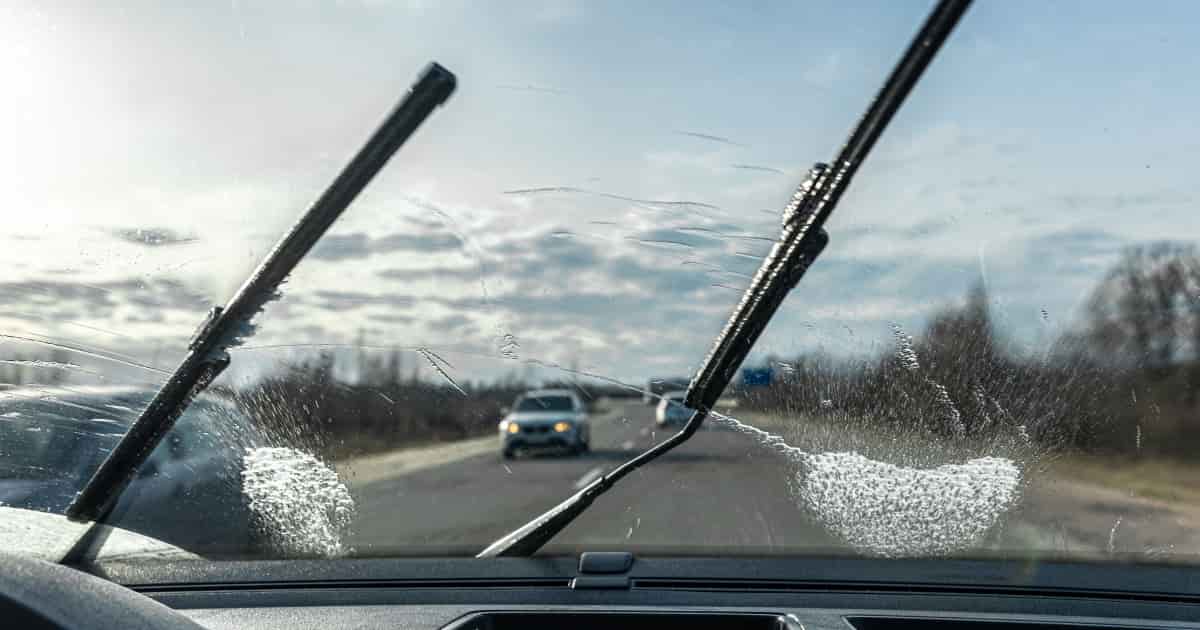 Car wipers clean windshields when driving in sunny weather.